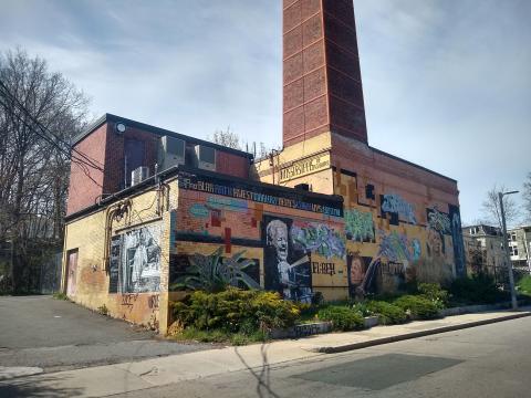 A brick building is covered in a multimedia mural.