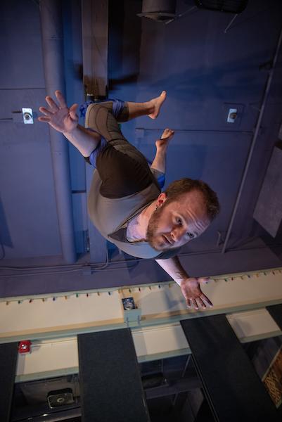 a person suspended by acrobatic silks with head arching and arms outstretched