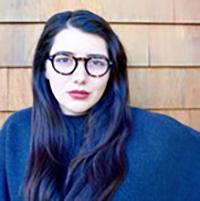 Danielle is a white woman who wears read lipstick and round, thick framed glasses with her long dark hair.