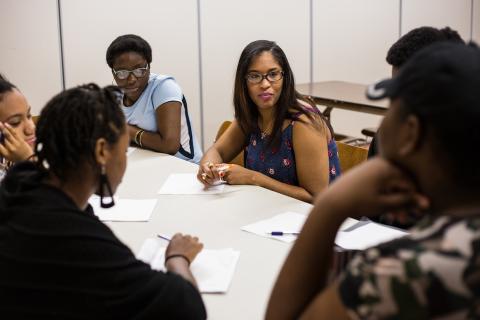 Fabiola leads a discussion with some young people around a table.
