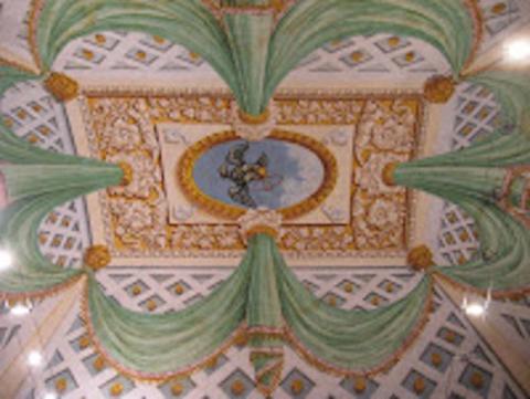 view of a fresco ceiling featuring light green drapes around a golden eagle