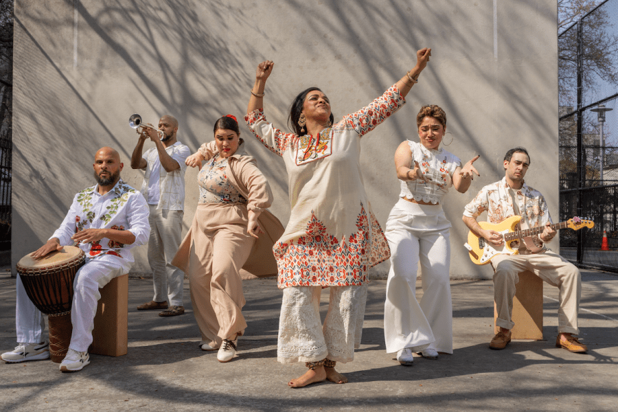A group of six people dressed in white strike poses outside.