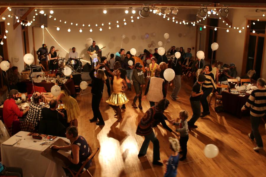 Overhead, of a party, where folks are dancing below stringed lights.