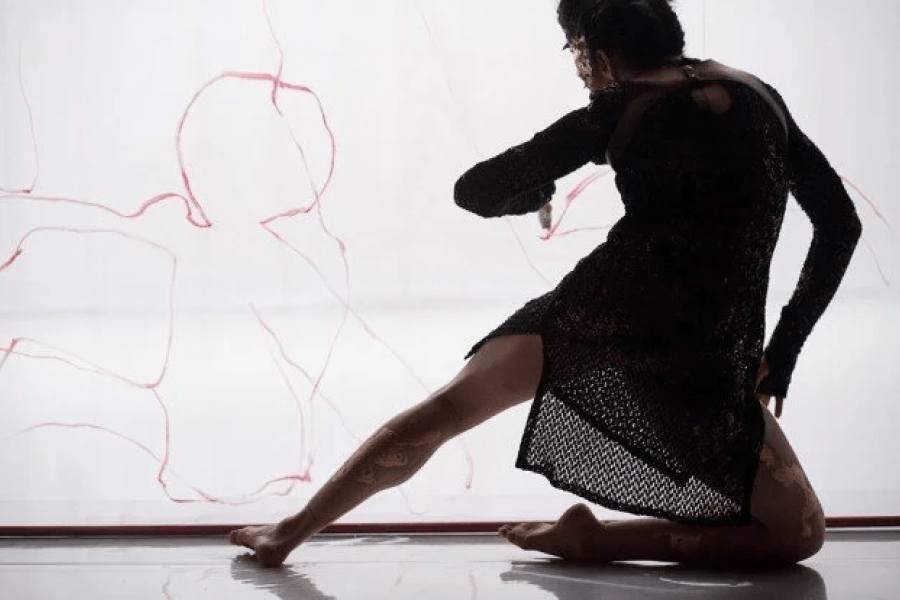 A dancer leans on a knee while stretching out a leg.