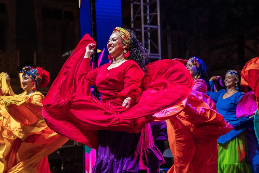 A dancer among a crowd of dancers, twirls her red dress.