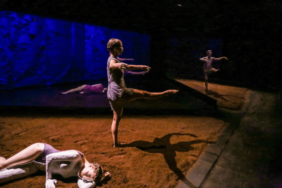 Two dancers twirl on a stage of dirt.