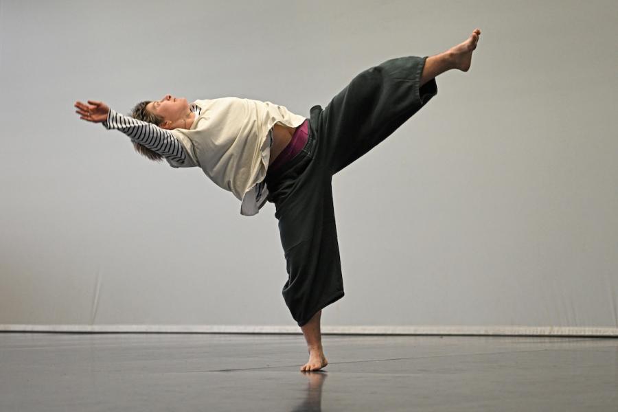 A dancer stands on one leg with the other leg and one arm extended above.