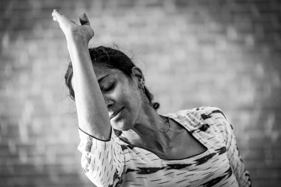 In black and white and in front of a brick wall, Mythili leans into her arm.