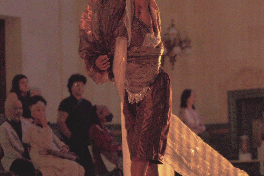 A performer poses in a hall, their face fully concealed by cloth.