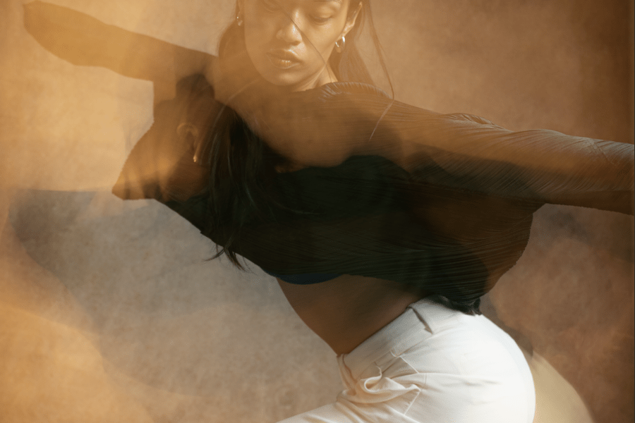 A hazy image of a dancer with a black top and white pants halfway through a move.