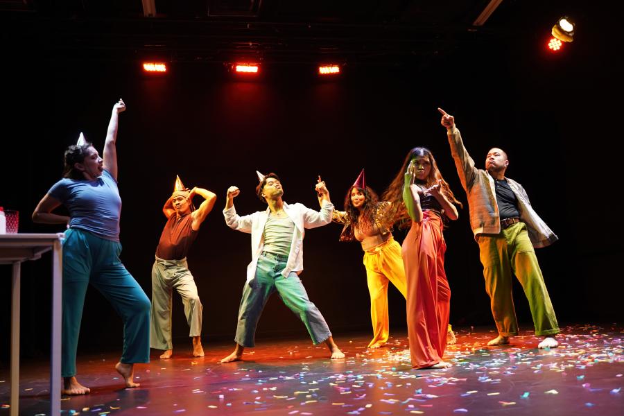 Six people pose on a confetti covered stage.