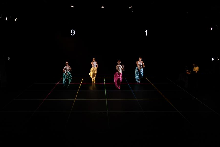 Wide shot of the four dancers in big pants on the lined floor.