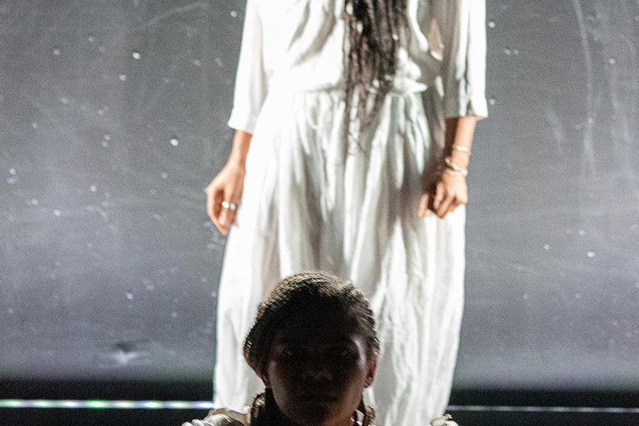 A woman is backlit and sits in front fo another woman in white pajamas.