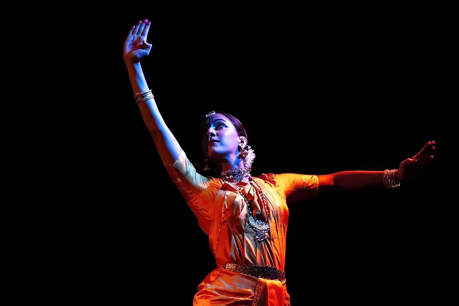 In a spotlight, Mythili dances in traditional Indian garb.