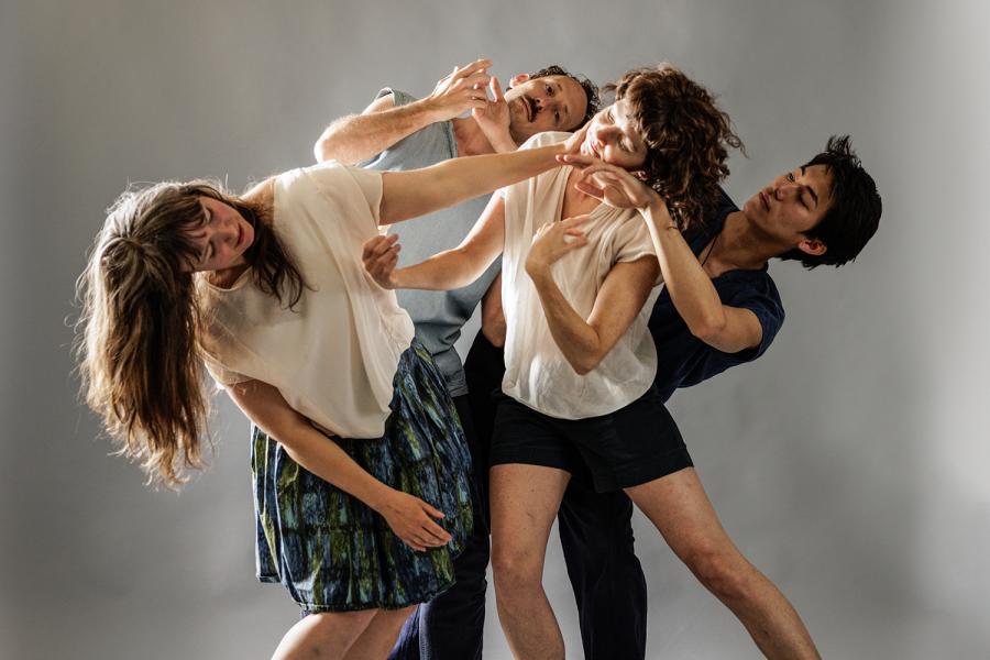 One woman leans away from a group who pull at her arms and another woman is in the middle of the group of four with her face touched by two of the performers.