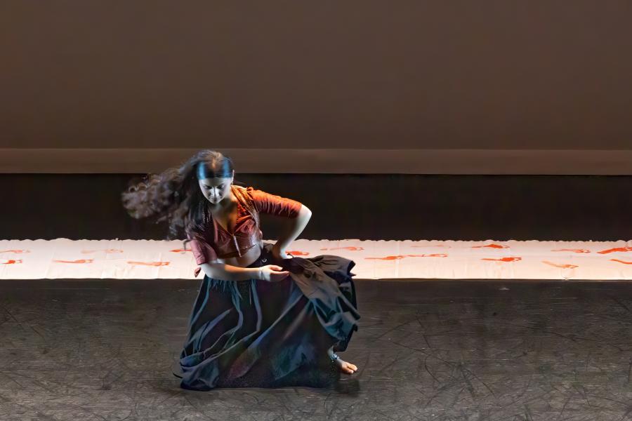 A performer in a long dark skirt strikes a crouching pose.