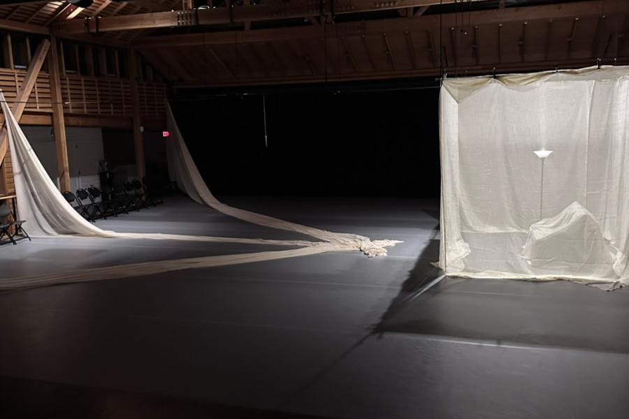 In a large room curtains drape from the ceiling forming a see through square.