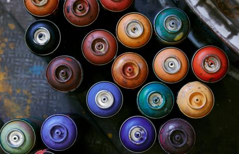 An overhead view of multi-colored spray paint cans.