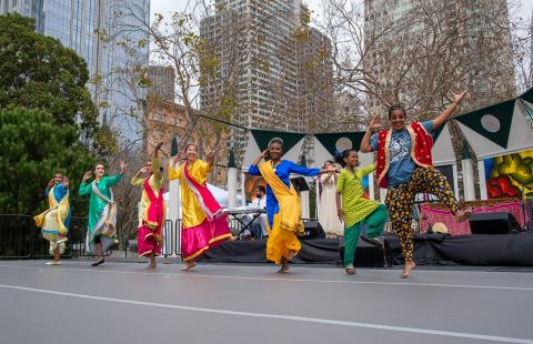 On an outdoor stage, seven women dance. 