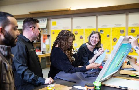 A group of people work on creating a screen print.