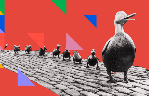A statue of a mother goose with a trail of ducklings behind her. A triangular pattern in bright colors just left of the ducklings.