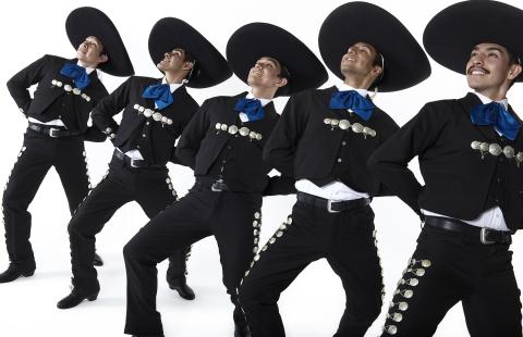 Five men in black mariachi outfits with blue ties lean back and smile in a line. 