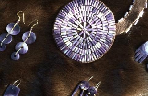 several pieces of wampum jewelry displayed on a dark brown fur-like background.