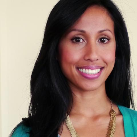 A smiling woman in a teal cardigan