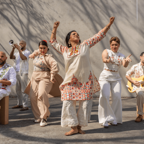 A group of six people dressed in white strike poses outside.