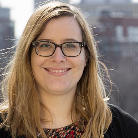 a head shot of a woman smiling; the Boston skyline is in the background.