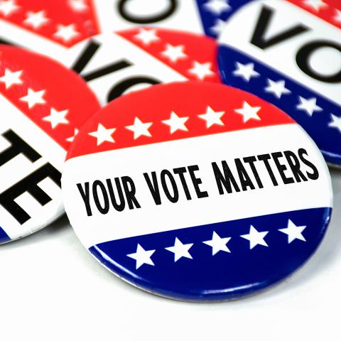 A pile of "Vote" pins in red and blue. One pin says "your vote matters."