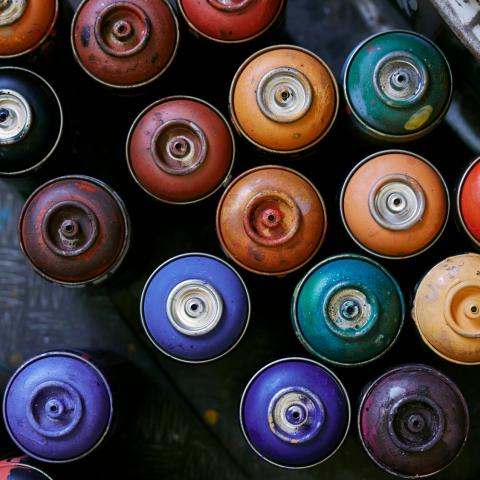 An overhead view of multi-colored spray paint cans.