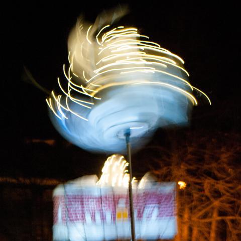 A swirling light installation makes lines of light against a black sky.