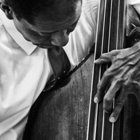 Black and white photo of a Black man playing the base.