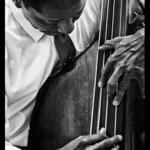 Black and white photo of a Black man playing the base.