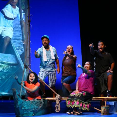 A girl in a "boat" and three people on a "dock" point out to the audience.