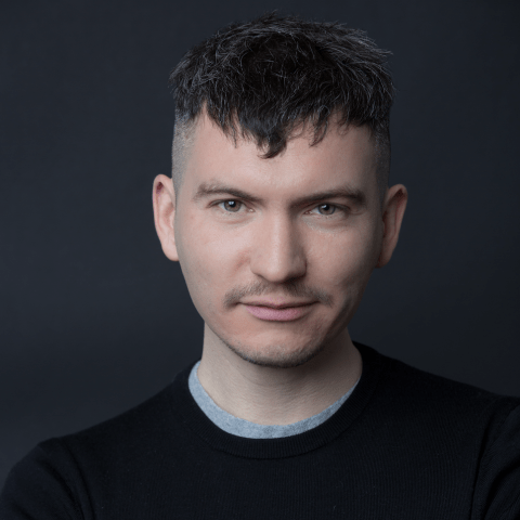Ben is a white man with gray and black hair. He has hazel eyes and wears a black sweater in front of a gray backdrop.
