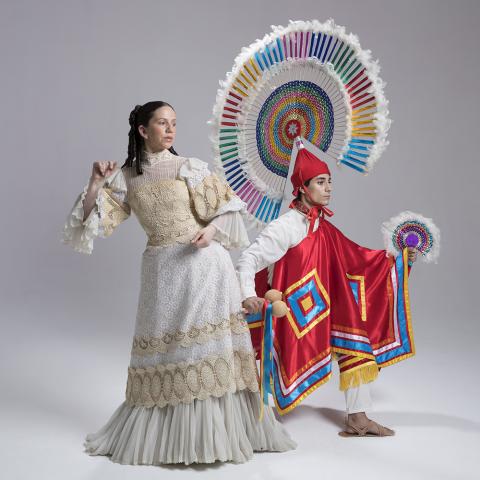 A man and a woman pose in traditional Mexican garb in a white walled studio space