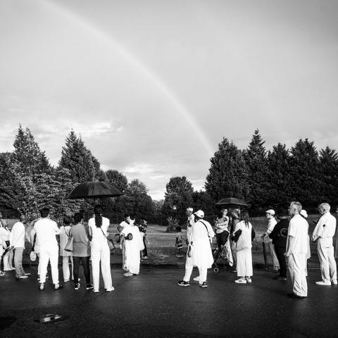 A group of folks stand in a parking lot next to a rainbow.