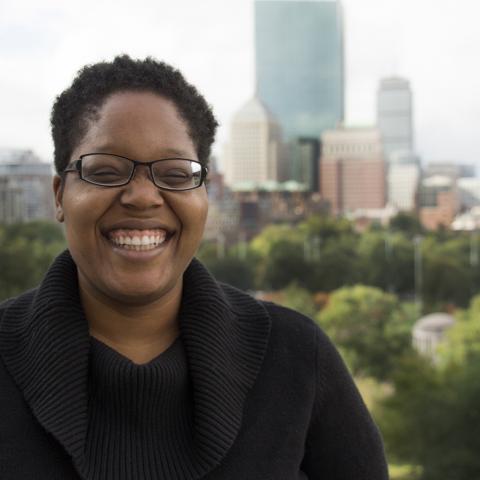 Deidra smiles in front of the Boston skyline