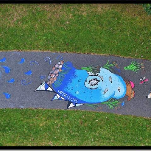 Overhead view of a sun, sea, and earth chalk mural on pavement.