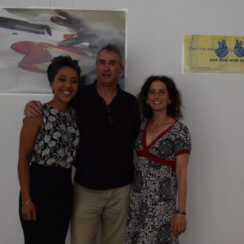 Lisa, Brad, and Suamy pose in front of a classroom wall, with educational posters behind them.