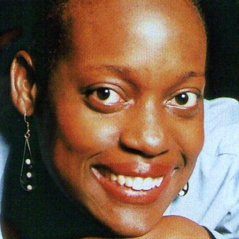 A smiling black woman with dangling earrings and a blue shirt