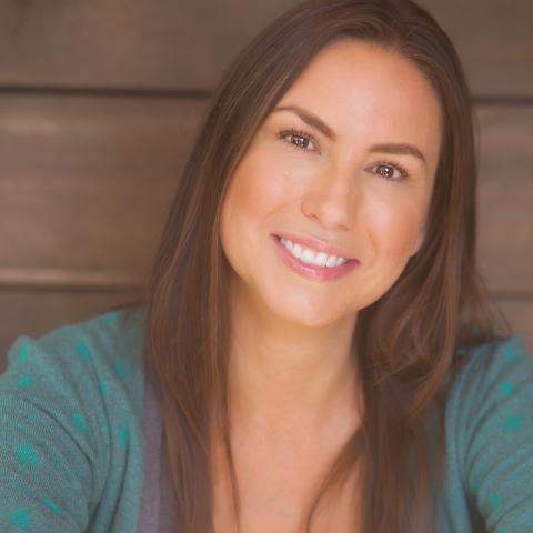 DeLanna has long brown hair with highlights. She smiles in a green cardigan over a gray t-shirt.