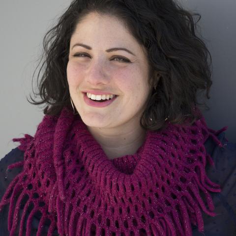 Denise smiles away from the camera, while wearing a pink knitted scarf