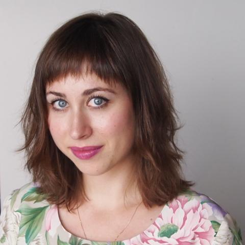 Elizabeth smiles in front of a gray wall