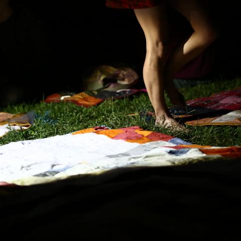 A woman walks over fabric laid over grass.