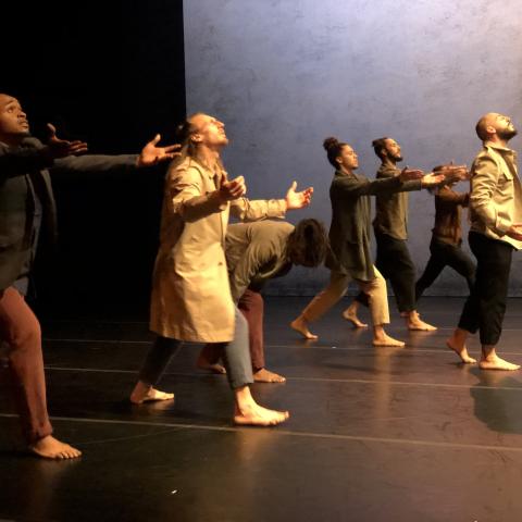 On a stage, six dancers in streetwear walk forward.