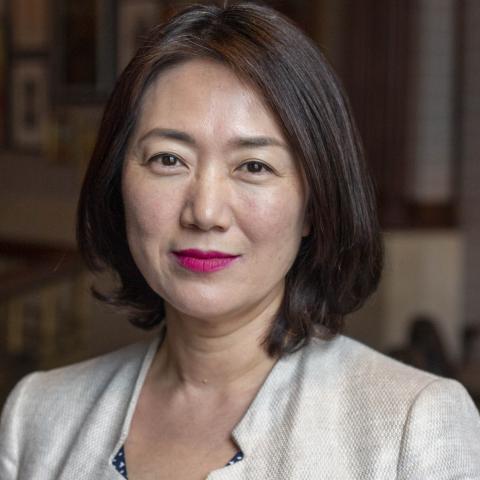 Head shot image of board member Min Jung Kim; she is smiling and wearing a ivory jacket.
