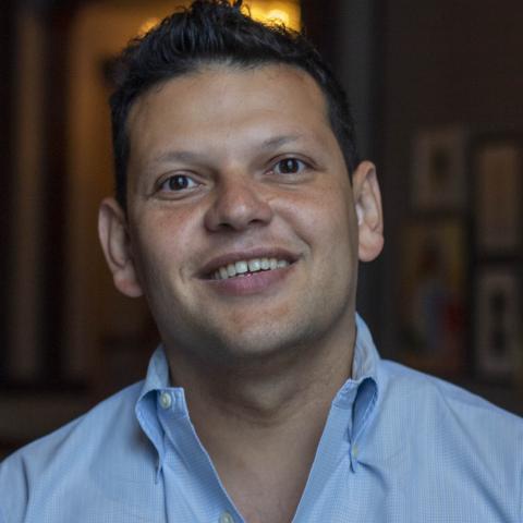 Head shot image of board member Ivan Espinoza-Madrigal; he is wearing a blue shirt and smiling.